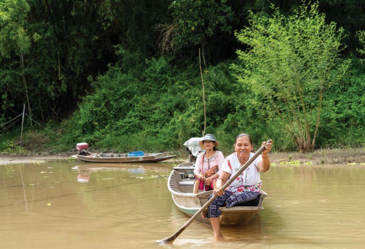 Rowing a wooden boat past the raft houses