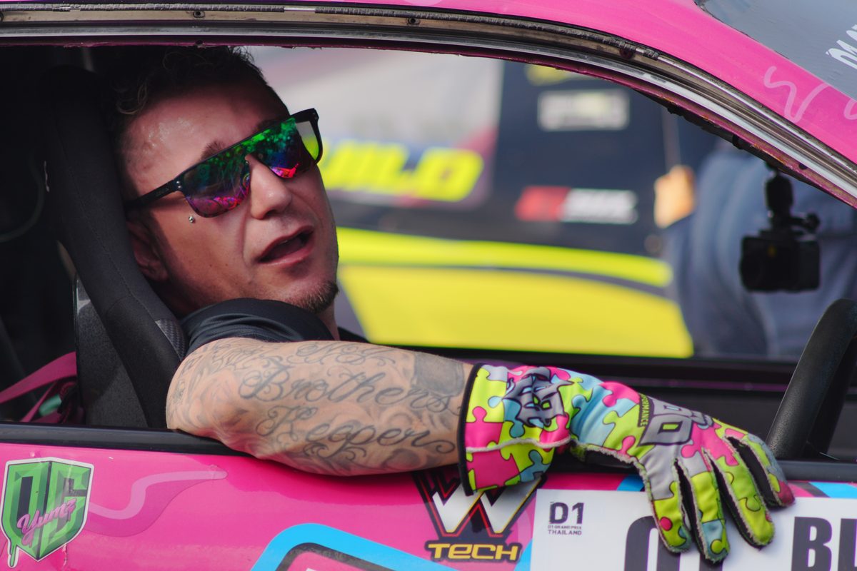 Driver in a pink D1 car, sunglasses and tattoos, gloves on the door